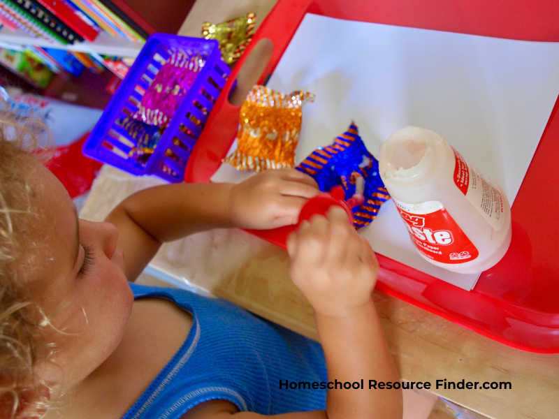 Homeschooling with a toddler. Image of a toddler gluing a montessori style activity