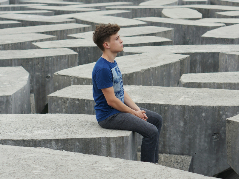 A boy sitting on bricks, thinking -how to teach homeschool maths basics without the drill and kill